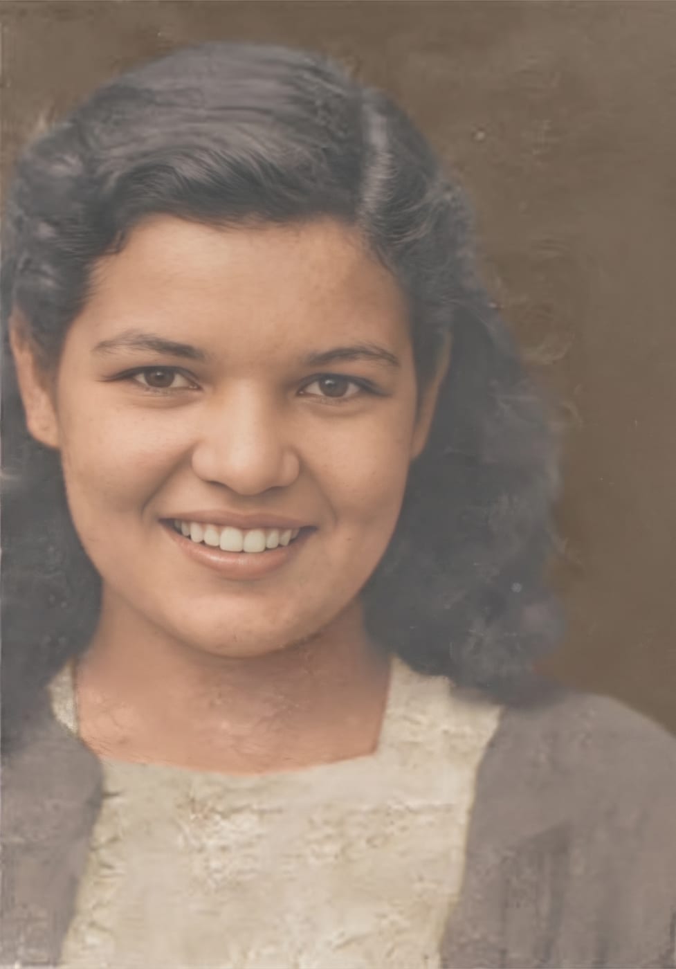Restored and colorized portrait of a smiling young woman with dark wavy hair