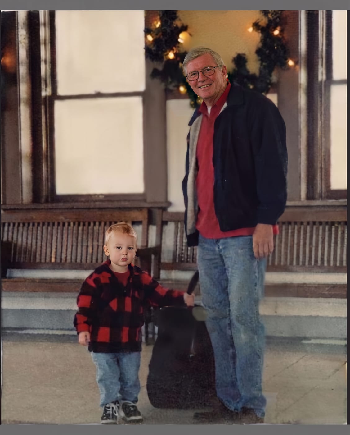 Restored colour photograph of a man in glasses and a small boy in a checked jacket on a street