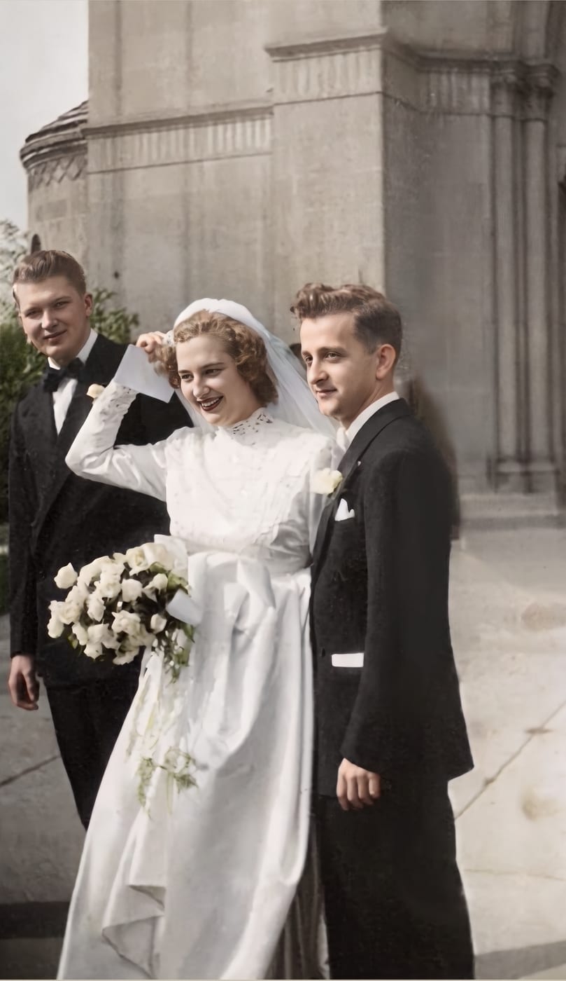 Restored and colorized 1940s wedding photograph of a bride, groom and best man outside a stone building